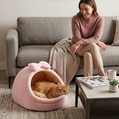 un chat se repose dans sa niche pour chat rose  